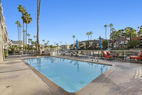 Outdoor swimming pool with seating area and surrounding buildings.