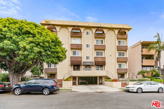 Front view of a multi-story apartment building with a symmetrical facade and brown balconies.