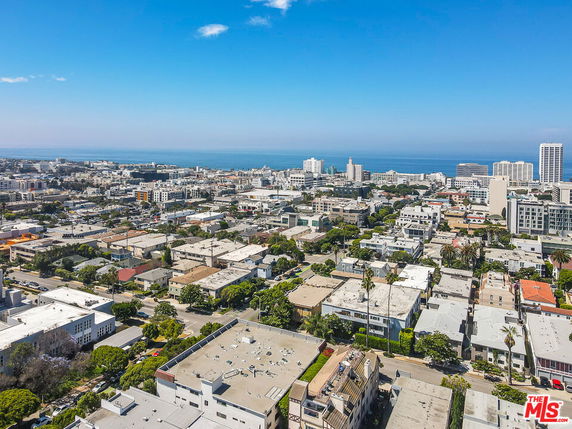 Panoramic view of a cityscape with residential and commercial buildings, overlooking the ocean.
