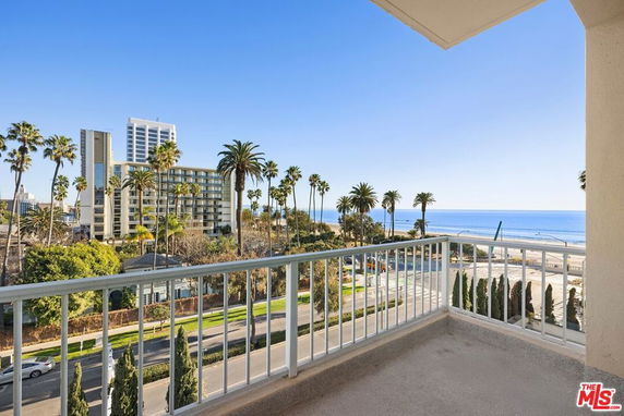 View from a balcony overlooking trees, buildings, and the ocean.