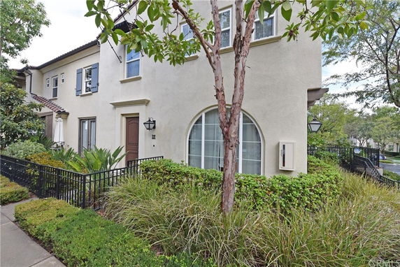 Front view of a multi-story house with beige walls and dark trim.