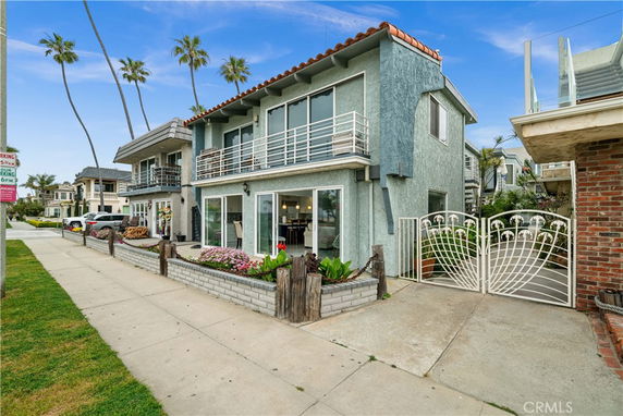 Front view of a two-story house with a balcony and gated entrance.