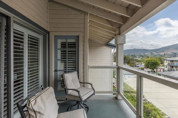 Balcony view from a building showcasing surrounding areas and hills.