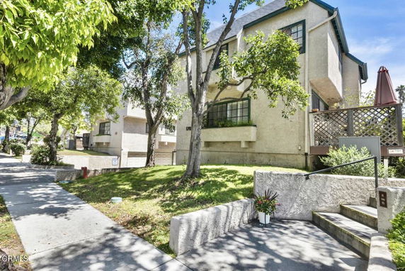 Front view of a multi-story residential building with a deck and trees around.
