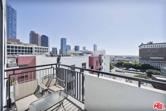 Panoramic view from a balcony overlooking a cityscape with modern high-rise buildings.