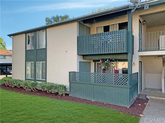 Front view of a two-story apartment building with balconies and a green lawn.