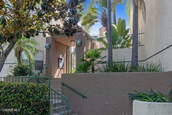 Front view of a building entrance with steps and a gated doorway.