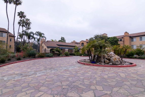 Front view of a large building with a circular driveway and palm trees.
