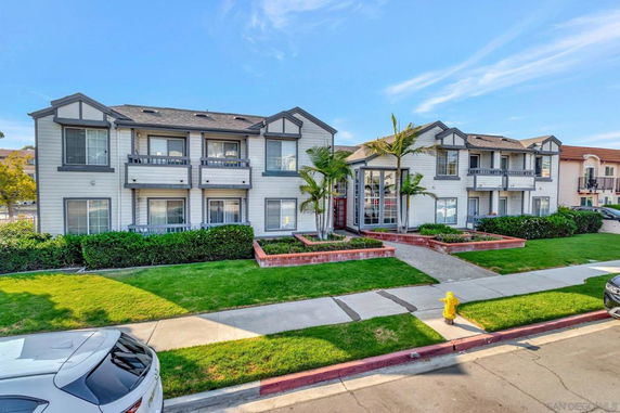 Front view of a two-story residential building with balconies and landscaping.