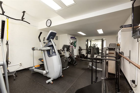 Indoor gym area equipped with exercise machines and weights.