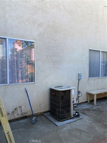 Exterior view of a building wall with windows and an air conditioning unit.