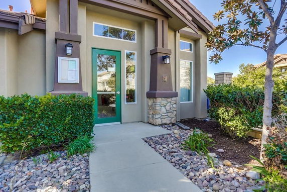 Front view of a house with a green door and stone accents.