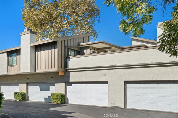 Front view of a townhouse with multiple garages and a flat roof.