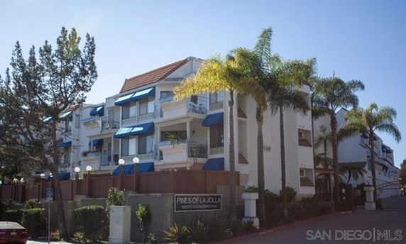 Front view of a multi-story apartment building with balconies and blue awnings.