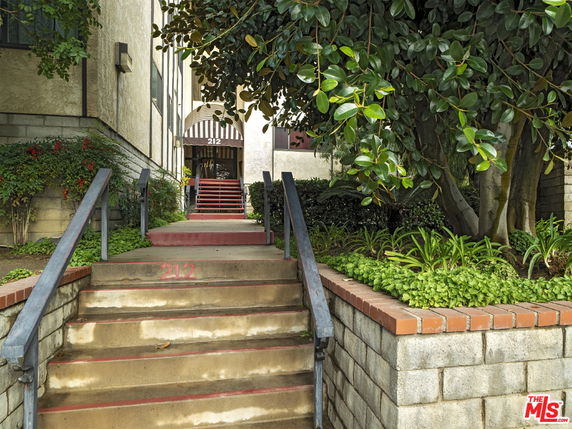 Front steps leading to the entrance of a multi-story building with a striped awning.