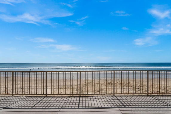 View of the ocean from behind a metal railing on a beachfront.