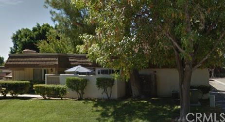 Front view of a single-story house with a flat roof and a fenced front patio.