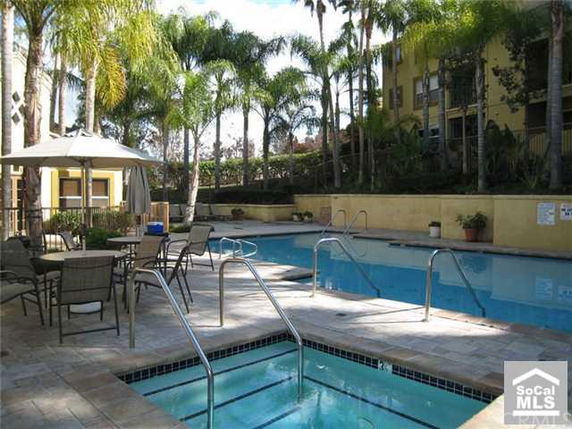 Outdoor area featuring a swimming pool with surrounding lounge furniture and tropical plants.