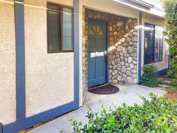 Front view of a house with a stone facade entrance and a blue door.