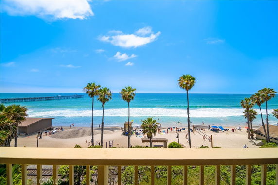 Beach view with ocean and palm trees from a balcony perspective.