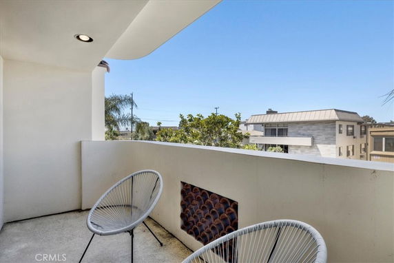 Outdoor balcony area with chairs providing a view of surrounding buildings.