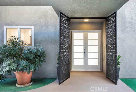 Front view of a building entrance with decorative gates and a potted plant.