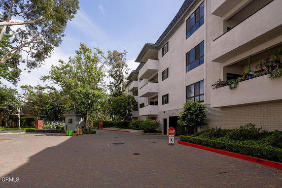 View of a multi-story residential building with balconies and surrounding trees.