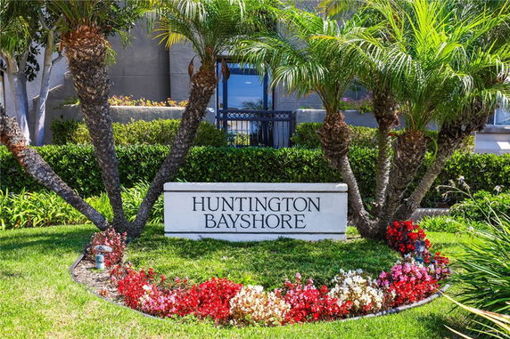 Front view of a building with a sign reading 'Huntington Bayshore' surrounded by plants and flowers.