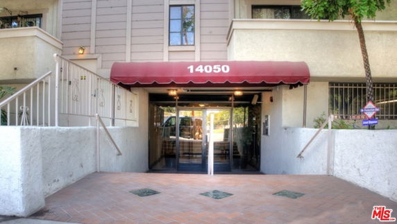 Front view of a building entrance with a red canopy and glass doors.
