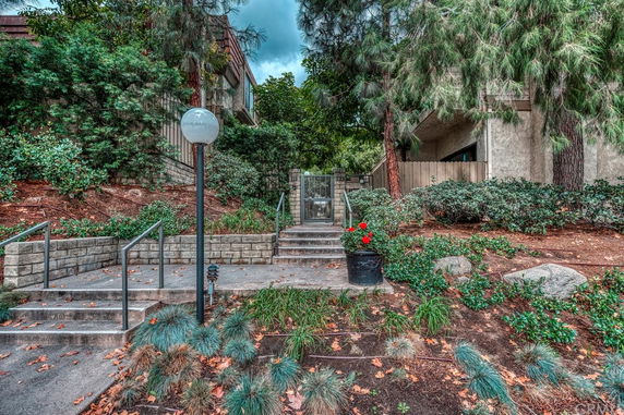 Front view of a building with landscaped entrance and stairs leading up to a gated doorway.
