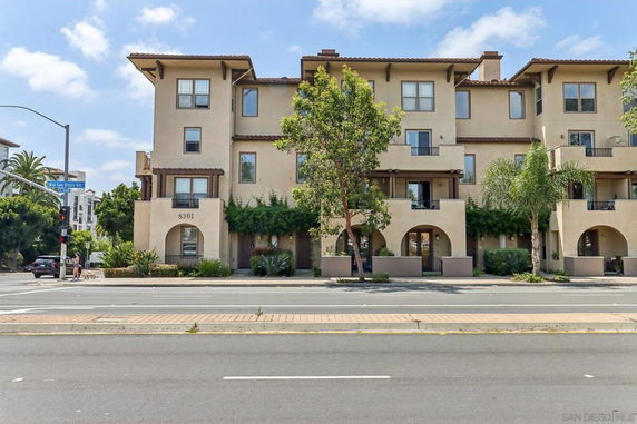 Front view of a multi-story residential building with balconies and arched windows.