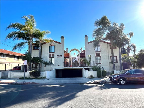 Front view of a multi-story building with distinct archways and palm trees in the foreground.