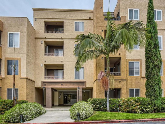 Front view of a multi-story apartment building with balconies and a central entrance.
