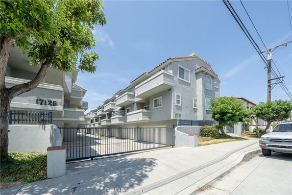 Front view of a multi-story apartment building with gated entrance and balconies.