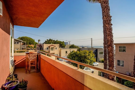 Outdoor view from a balcony overlooking residential buildings and trees.