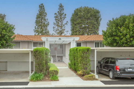 Front view of a two-story house with a tile roof and carport.