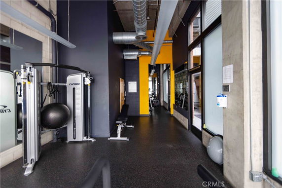 Interior view of a gym area with fitness equipment and bright yellow and grey walls.