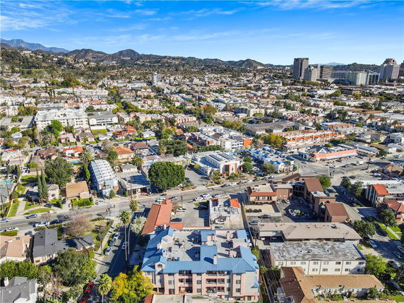 Wide aerial view of an urban area with numerous buildings and distant mountains.