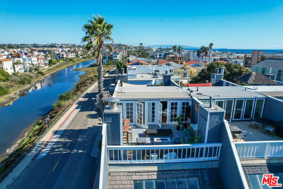 Rooftop view featuring a sitting area on a building with city and waterway surroundings.