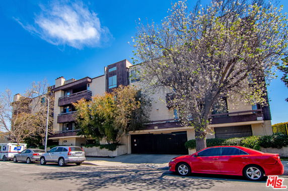 Front view of a multi-story residential building with balconies and parking area.
