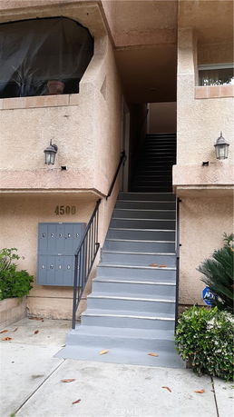 Front view of a multi-story building with stairs leading to the entrance.