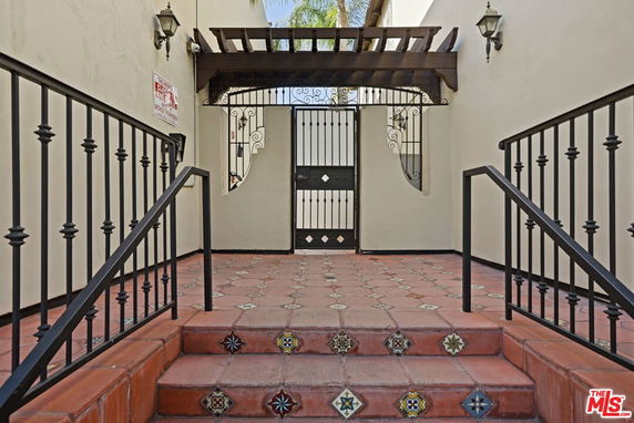 Front entrance of a building with decorative tile steps and wrought iron gate.