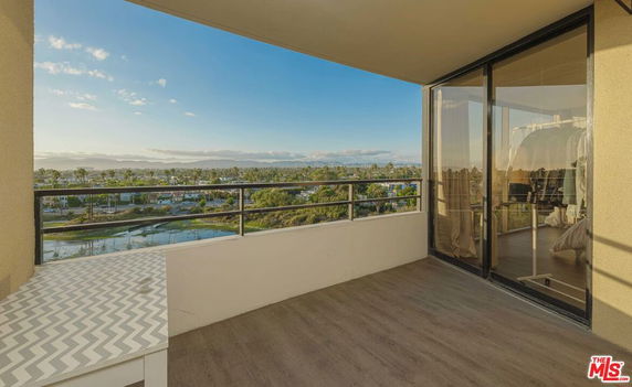 Balcony view overlooking a residential area with a river and distant mountains.