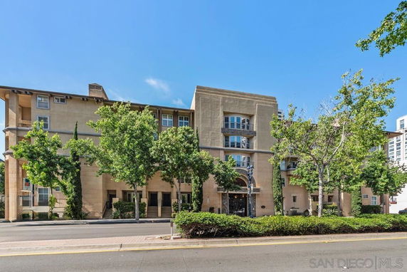 Front view of a multi-story residential building with trees along the street.