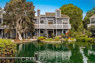 Front view of a two-story house with balconies overlooking a pond.