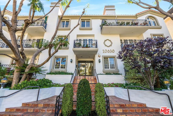 Front view of a multi-story residential building with balconies and decorative railings.