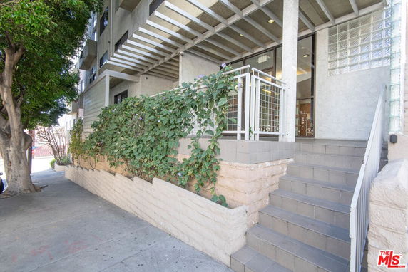 Entrance view of a building with stairs and railing.