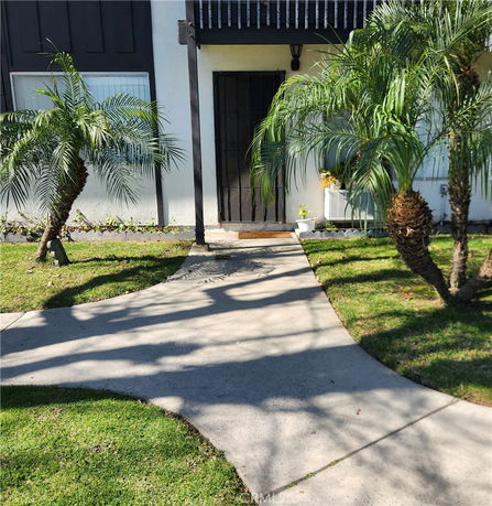 Front view of a house with a walkway and palm trees
