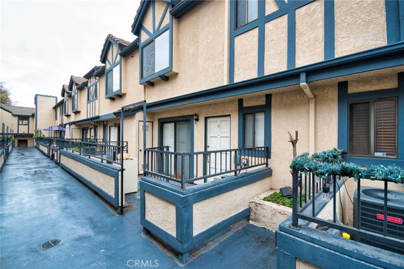 Front view of a row of connected two-story houses with blue trim and small porches.