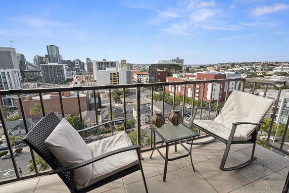 View of cityscape from a balcony with two chairs and a small table.